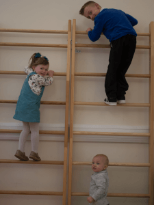 Three children climbing on an indoor gym climbing wall.