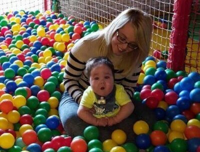 Child with his mum in a colourful ball pit.