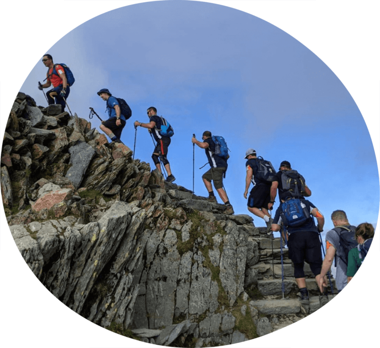 A long line of men climbing to the summit of a mountain