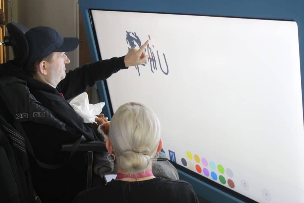 A man in a wheelchair playing with an interactive screen