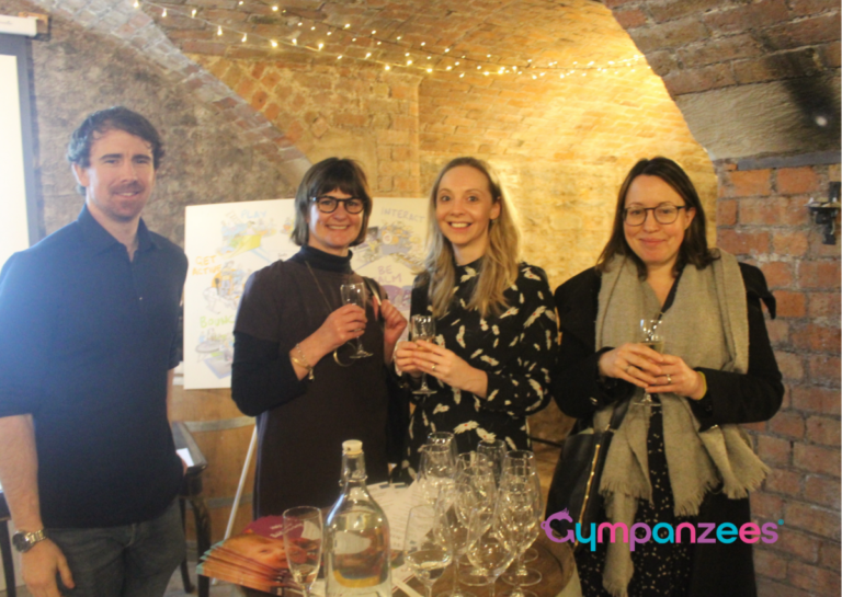 Four people stood together drinking wine