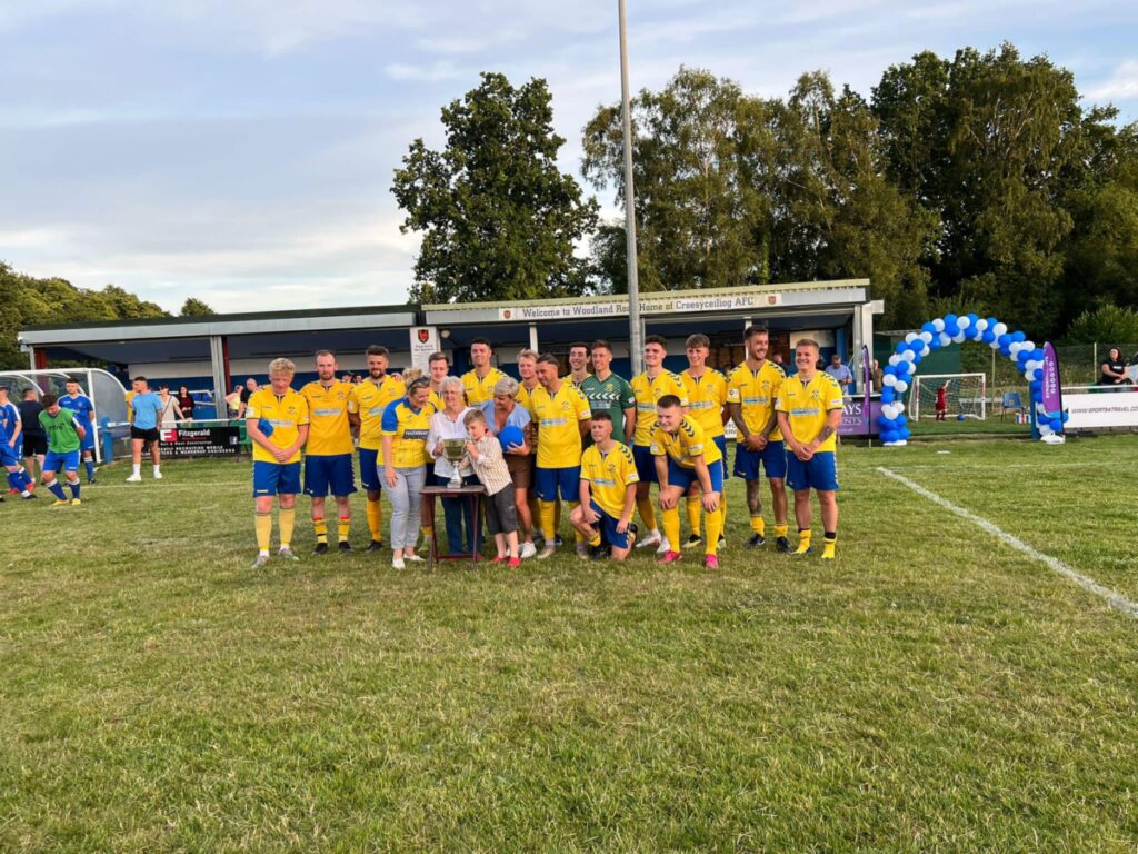 A football team in yellow are stood with a family with donation buckets