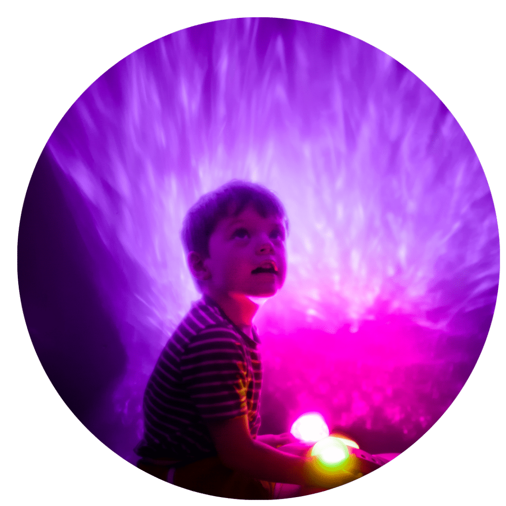 A young child playing with fibre optic lights in a dark sensory room