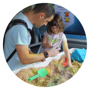 A parent and child playing in an interactive sandpit