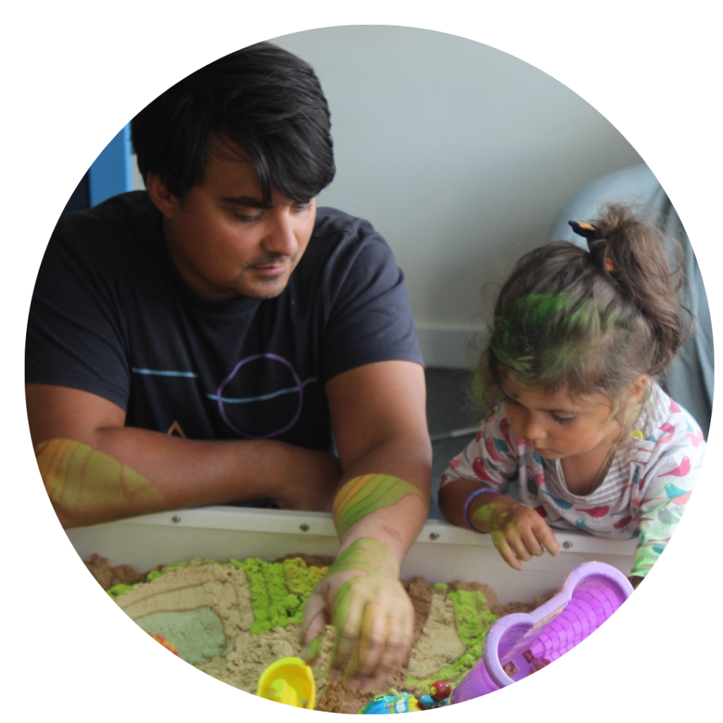 A parent and young child using an interactive sandpit