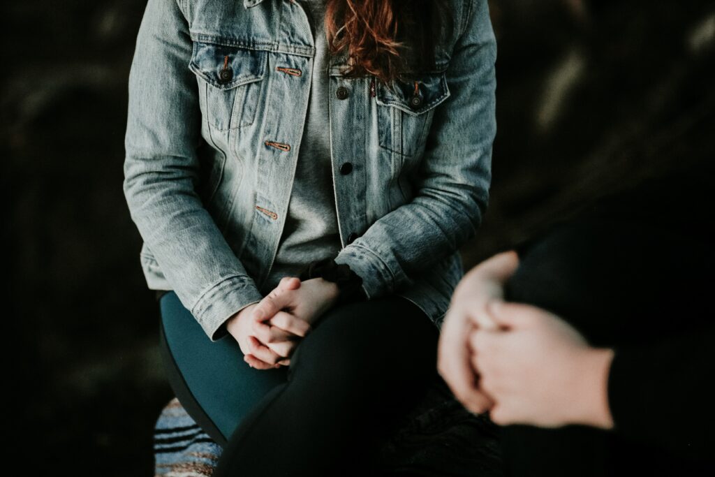 Two people sat opposite each other with their hands together.