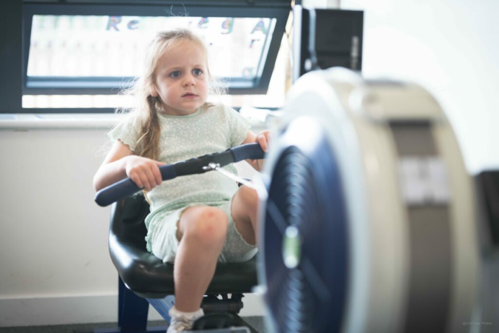 A little girl using an adapted rowing machine